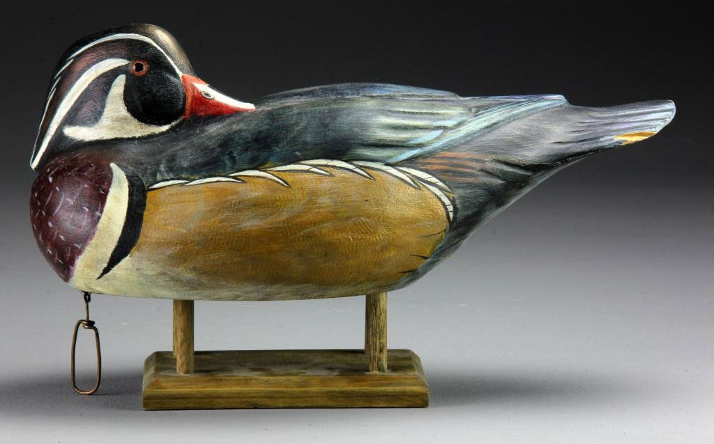 Lou Petrucco, MD Grosse Ile, MI Carved Duck Decoy: Finely carved as a wood duck with back turned head and inset glass eyes, bottom of carving states, "Lou Petrucco, MD Grosse Ile, MI. Many Puddle Ducks Were Shot Over This Decoy By Gibraltar Bay, Lake