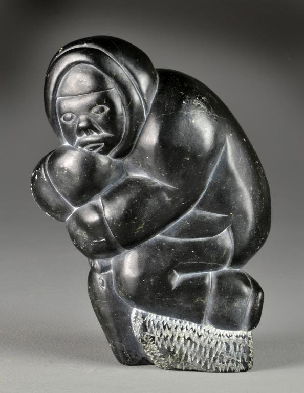 An Inuit Carved Soapstone Figural Sculpture: Finely carved to depict the head of an Eskimo and the head of a walrus, it appears to be signed and numbered to the bottom with remnants of additional paper labels, a very heavy sculpture measuring 10