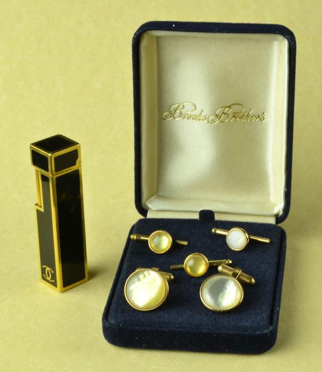 Cartier Lighter and Brooks Brother Cufflink Set: To include a Cartier 18K gold plated and black enamel lighter, together with a cuff link and tie set each set with moon stones, lighter is 2.5"H. Provenance: Formally in the collection of Gary Culpepp