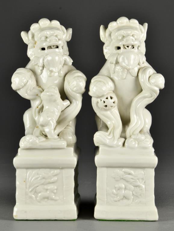 Pr. Chinese Blanc de Chine Porcelain Foo Dogs: Molded to depict foo dogs atop a plinth, one with a ball the other with a smaller foo dog playing at its feet, 10.75"H, circa mid-20th century. Private collection Dearborn, Michigan.