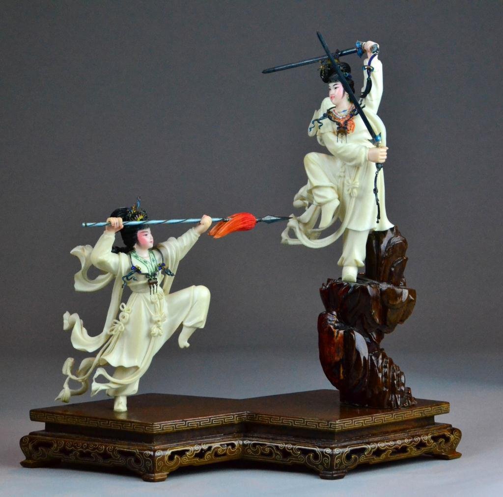 Chinese Polychrome Painted Ivory Warriors On Stand: Carved to depict two female warriors on stand, each warrior wearing enamelled jewlery and holding metal weapons also enamelled, intricatley carved this may be one of the finest pieces we've seen, rais