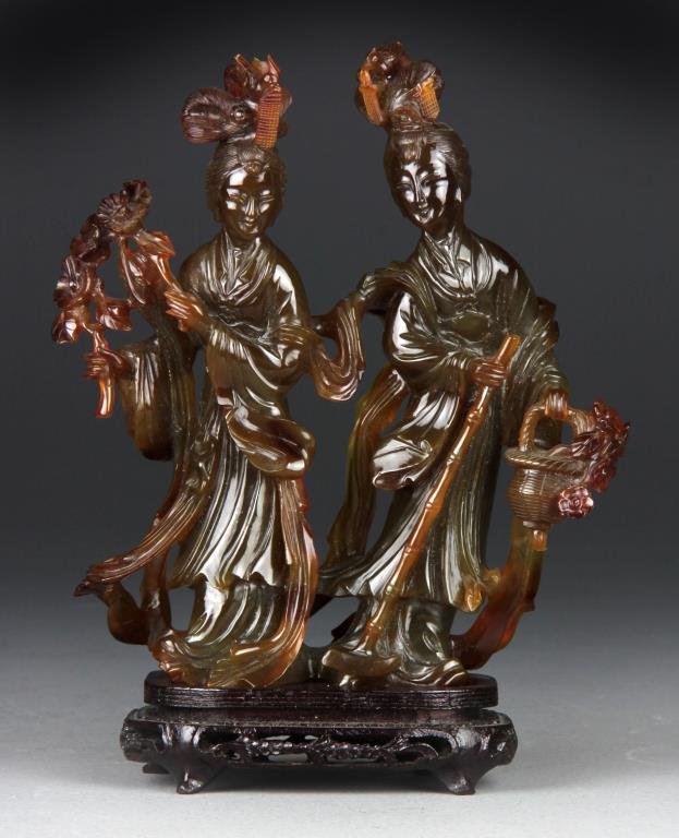 Chinese Agate Figural Carving On Stand: Finely carved as two beauties, one holding a staff and basket of flowers and the other holding flowering branches, raised on carved hardwood stand, 10"H with stand. Property from Ethel Miller Siegel T