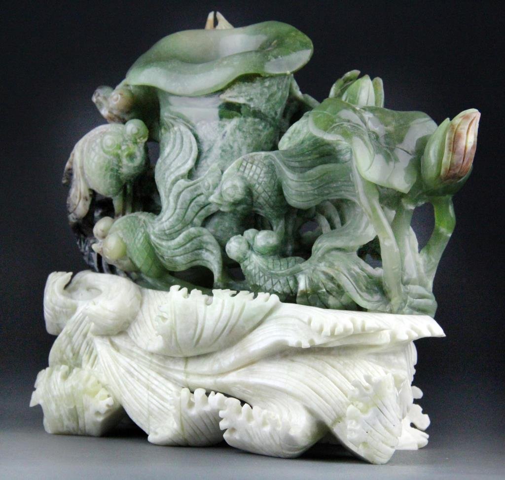 Chinese Jade Carving of Goldfish and Lotus: Finely carved jade from green to rust color depicting popeyed goldfish and lotus pads raised on a white jade base carved to depict waves, 9.5" H x 10.5" L including base, circa 20th century, good cond