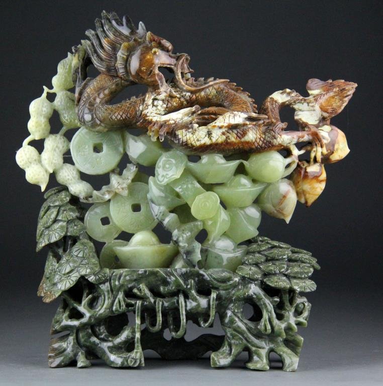 Chinese Jade Carving of Dragon, Peanuts, Coins: Finely carved jade in light green to brown depicting a dragon, bats, coins, peanuts and peaches raised on a dark green carved jade base , 11.5" H x 9" L including base, circa 20th century, good condit