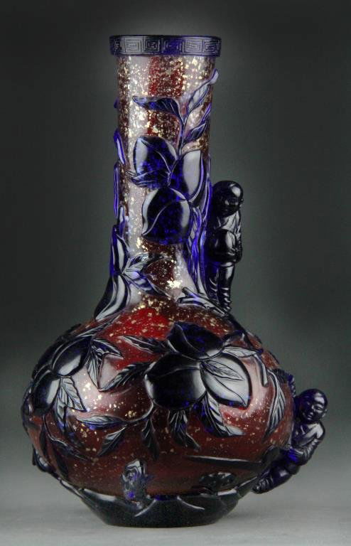 Chinese Peking Glass Vase - Cobalt/Red: Narrow-necked vase with bulbous body having cobalt blue overlay over red ground with gold flecks, Greek Key design on rim, body carved with peach branches along with two applied children on sides each