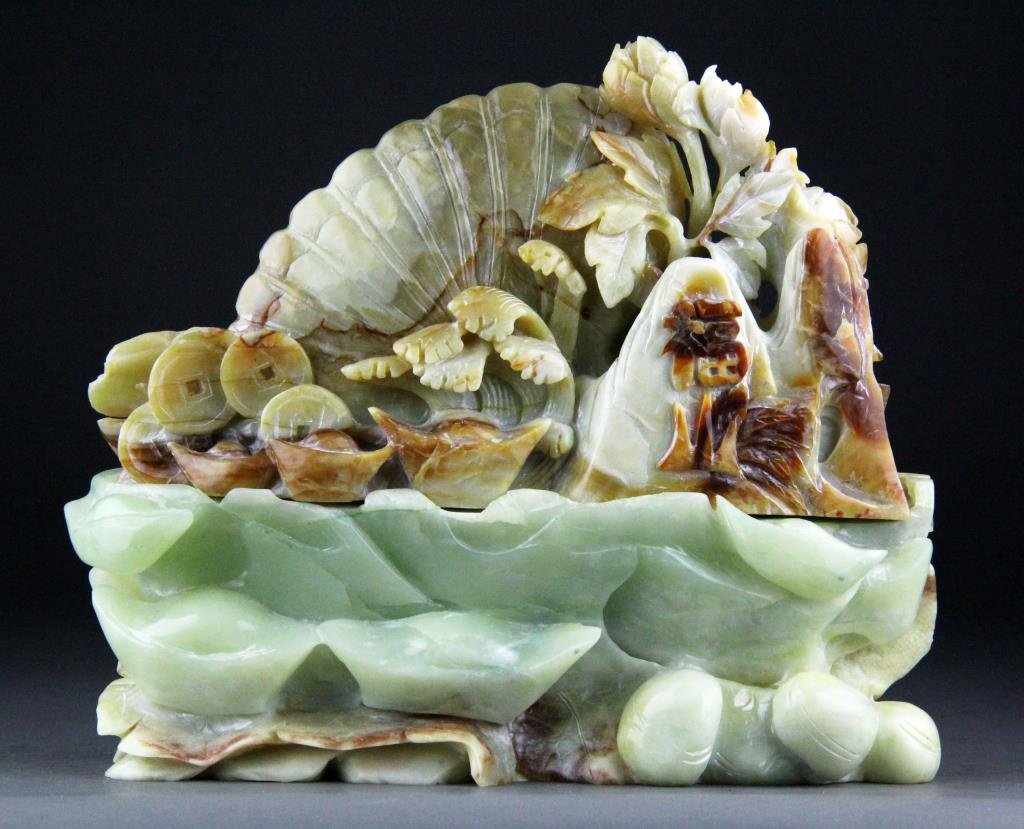Chinese Jade Carving of Shell, Coin Ingots and Bats: Finely carved green to amber colored jade depicting a large shell surrounded by coins, coin ingots, flowers and bats raised on a carved light green base depicting same, 9" H x 11" L including base, ci