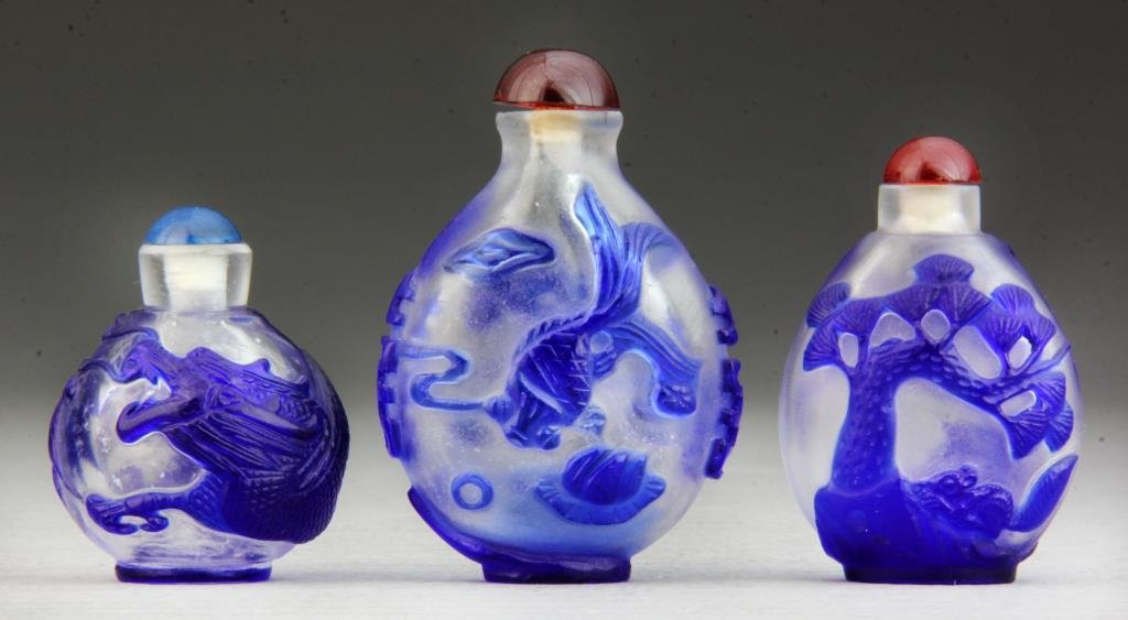 (3) Pcs Chinese Peking Glass Snuff Bottles: Fine overlay of coy fish with Chinese characters along sides, second depicting squirrel within landscape, third depicting full-bodied dragon, tallest is 3"H. Condition: good, all complete with stopper