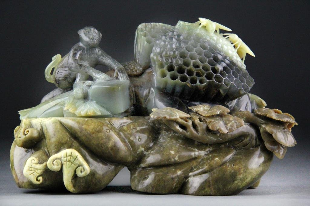 Chinese Jade Carving of Monkey, Honeycomb & Bees: Finely carved jade depicting monkey and honeycomb in dark green jade, yellow jade bees along with brown and white jade base, 6" H x 9.5" L including base, circa 20th century, damage to two wings and o