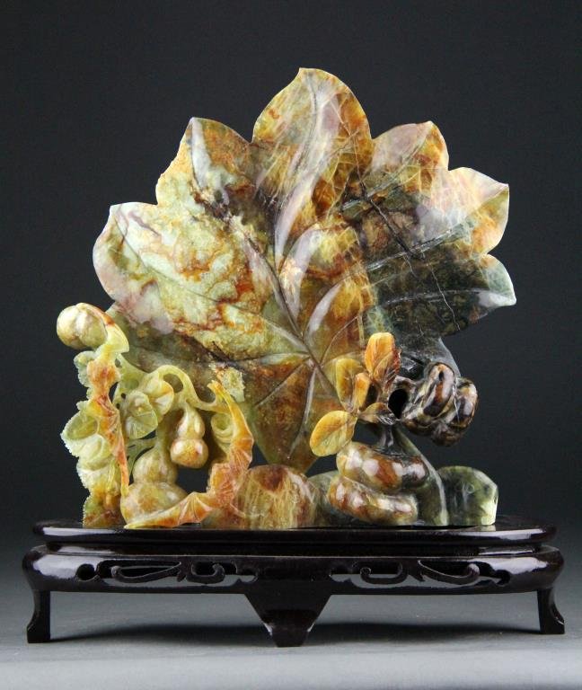Chinese Jade Carving of Leaf and Bats: Finely carved varigated amber colored jade depicting large leaf with bats and gourds along with wooden stand, 8.5" H x 8.5" L, circa 20th century, good condition.
