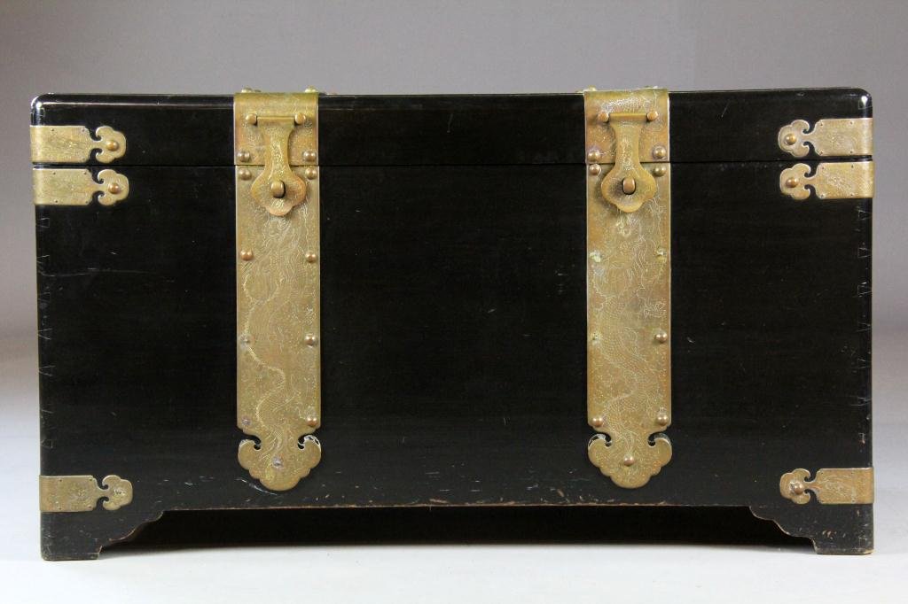 A Majestic Co. Chinese Hardwood Chest: Decorated in heavy brass strap work, hinges, and handles, with handcut dovetail construction, raised on four shaped feet, the interior with fitted pull out tray, with metal tag for Majestic Co. Hong K