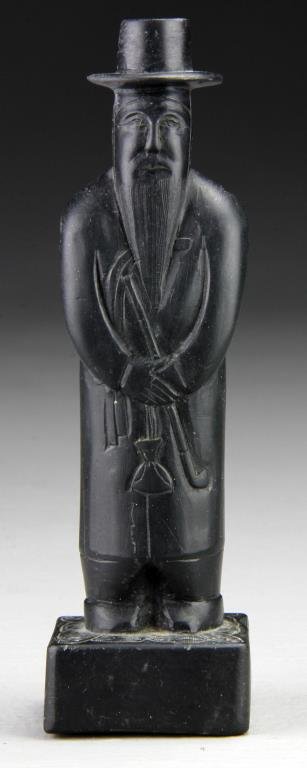 Chinese Soapstone Carving Of Charlie Chan: Depicting a standing Charlie Chan with an overcoat holding what appears to be a medicine bag, 6.75"H, circa early 20th century. Provenance: Formally in the collection of Gary Culpepper of Culpepper Ga