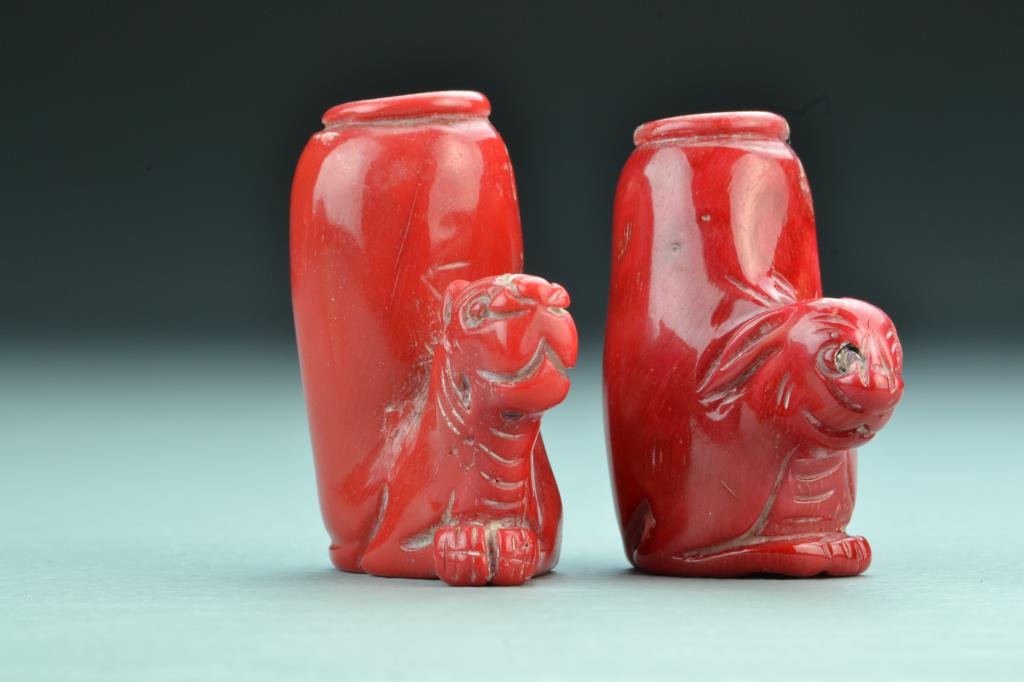 (2) Chinese Coral Snuff Bottles: Finely carved to depict a rabbit head and tiger head respectively, some surface imperfections, both lack stoppers, tallest is 2.25"H. From the collection of David Bell who worked for an Italian steel 