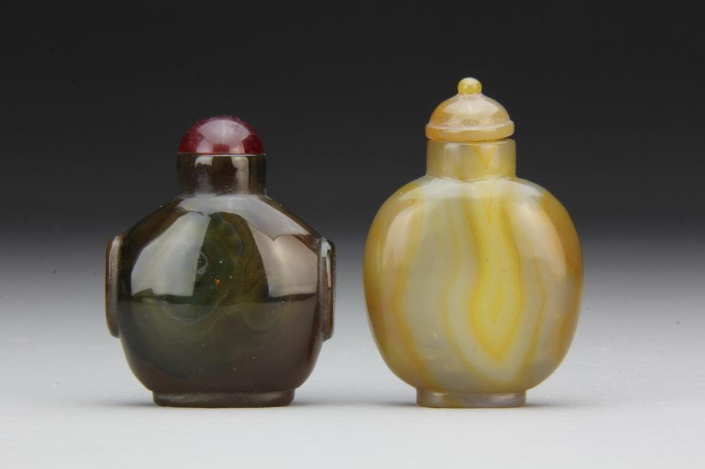 (2) Chinese Carved Agate Snuff Bottles: Finely carved and polished of simple form, showing natural properties of stone, one with beast head handles, complete with stoppers, tallest is 2.6"H. From the collection of David Bell who worked for 