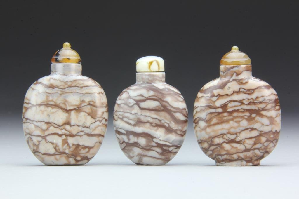 (2) Chinese Carved Agate Snuff Bottles: Finely carved and polished of simple form, showing natural lines of stone, complete with stoppers, tallest is 2.75"H. From the collection of David Bell who worked for an Italian steel company in China