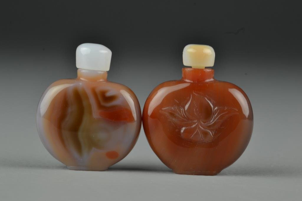 (2) Chinese Carved Agate Snuff Bottles: Very finely polished to show natural properties of the stone, one carved to depict plant, complete with stoppers, tallest is 2"H. From the collection of David Bell who worked for an Italian steel comp