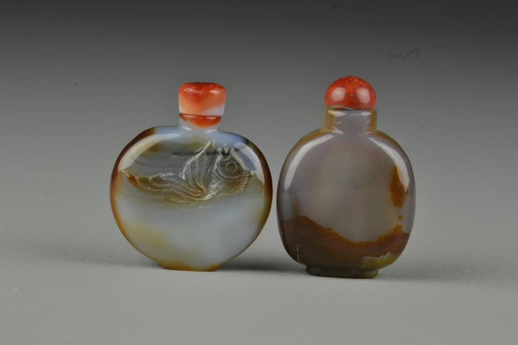 (2) Chinese Carved Agate Snuff Bottles: Very finely polished to show natural properties of the stone, one carved to depict fish, complete with stoppers, tallest is 2.4"H. From the collection of David Bell who worked for an Italian steel com