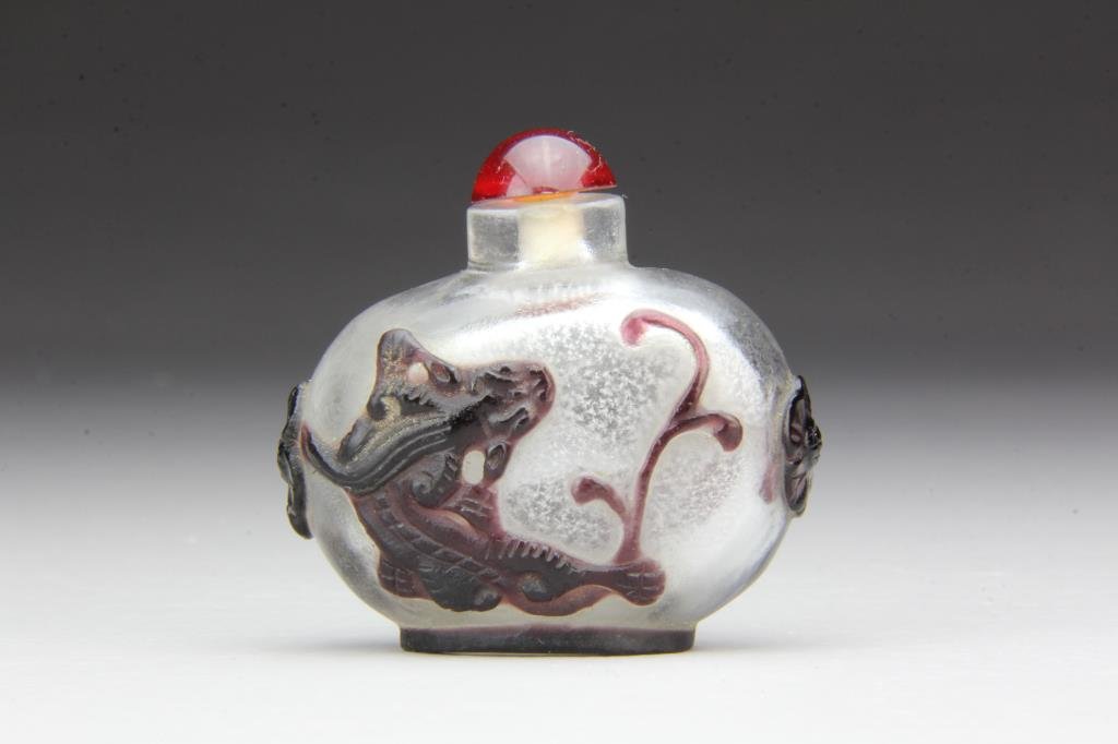 Chinese Peking Glass Snuff Bottle: Fine overlay depicting a chi long, flower on sides, complete with stopper, 2.25"H. From the collection of David Bell who worked for an Italian steel company in China during the 1980's.