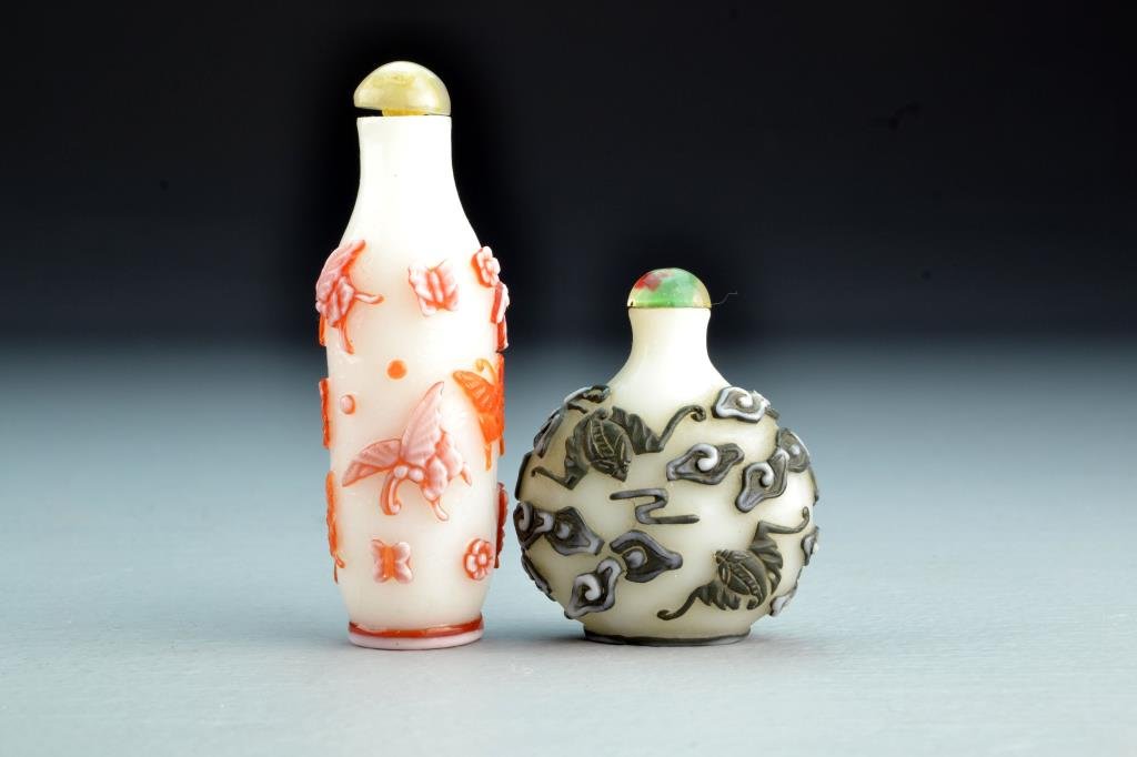 (2) Chinese Peking Glass Snuff Bottles: Each opaque glass with dual-colored overlay, one depicting moths and flowers, the other depicting bats among ruyi clouds, tallest is 3.7"H. From the collection of David Bell who worked for an Italian 
