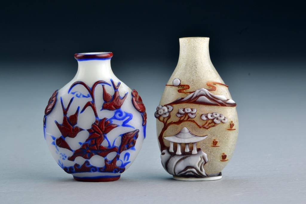 (2) Chinese Peking Glass Snuff Bottles: One having fine overlay depicting birds, lotus, ruyi clouds, bats and pomegranates, having beast head handles, other bottle depicting pagoda in a landscape, tallest is 2.75"H. From the collection of D