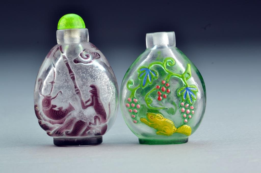 (2) Chinese Peking Glass Snuff Bottles: One havign colorful overlay depicting squirrel and grapes, other depicting bats and symbols with animal holding fishing pole under ruyi cloud on reverse, tallest is 2.9"H. From the collection of David