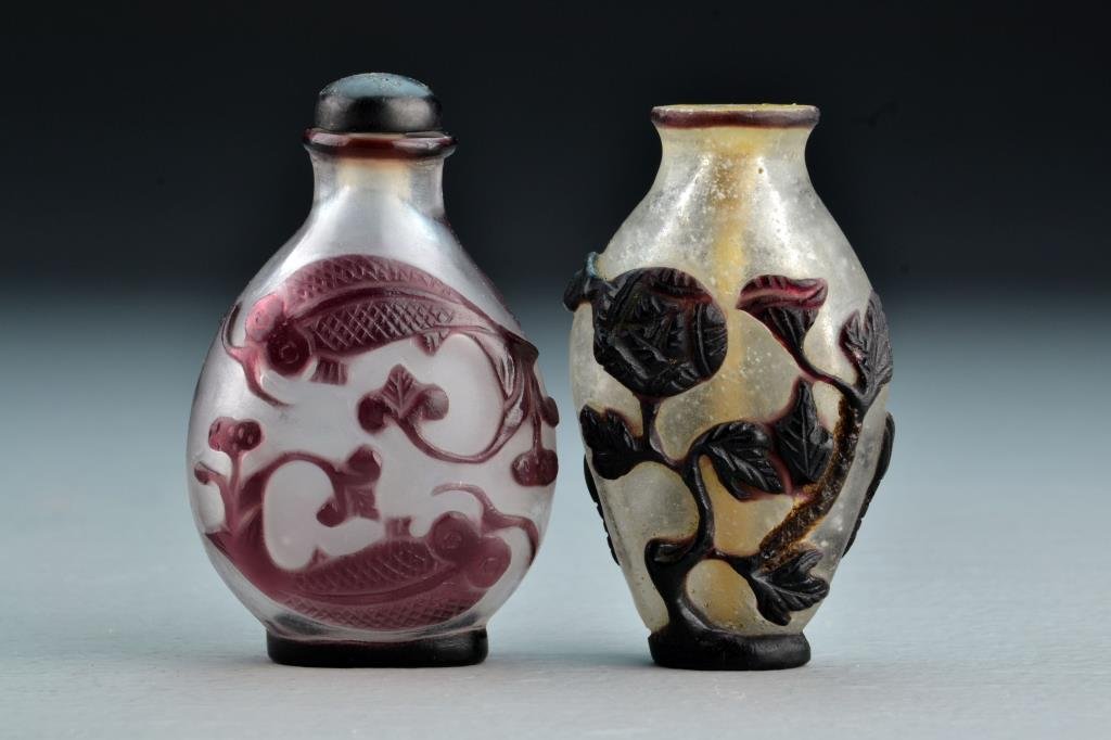 (2) Chinese Peking Glass Snuff Bottles: One having overlay depicting bat, symbol and flowers, other depicting koi fish with scrolling fins, tallest is 2.7"H. From the collection of David Bell who worked for an Italian steel company in China