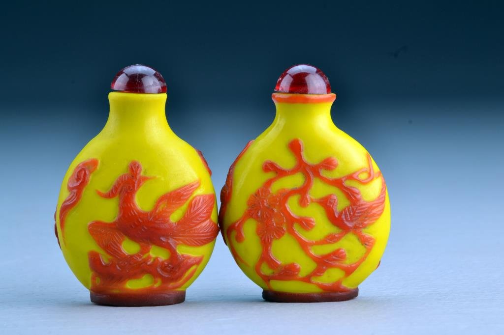 (2) Chinese Peking Glass Snuff Bottles: One with overlay depicting bat, fruit, bird and flowering branches, second depicting bats, an antique and a phoenix, tallest is 3.7"H. From the collection of David Bell who worked for an Italian steel