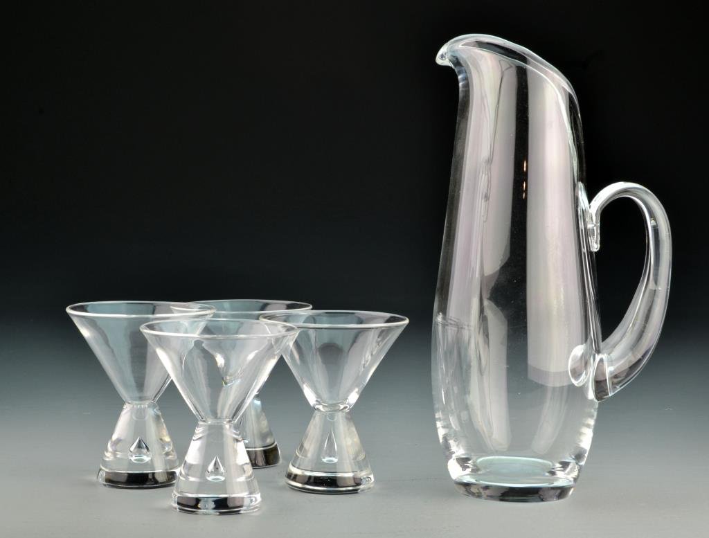 Stueben Five Piece Beverage Set: In a modernistic taste, having a handled carafe, and five footed cups. Carafe measures 10"H, condition excellent. Private Collection, Lake Orion, Michigan.