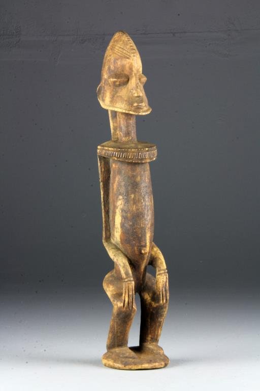 Antique African Carved Wood Ancestral Figure: A finely carved wood figure in a seated position with rounded hips, having carved details depicting hair, facial hair, and jewelry, measures 19"H, circa late 19th-early 20th century. Collection of the