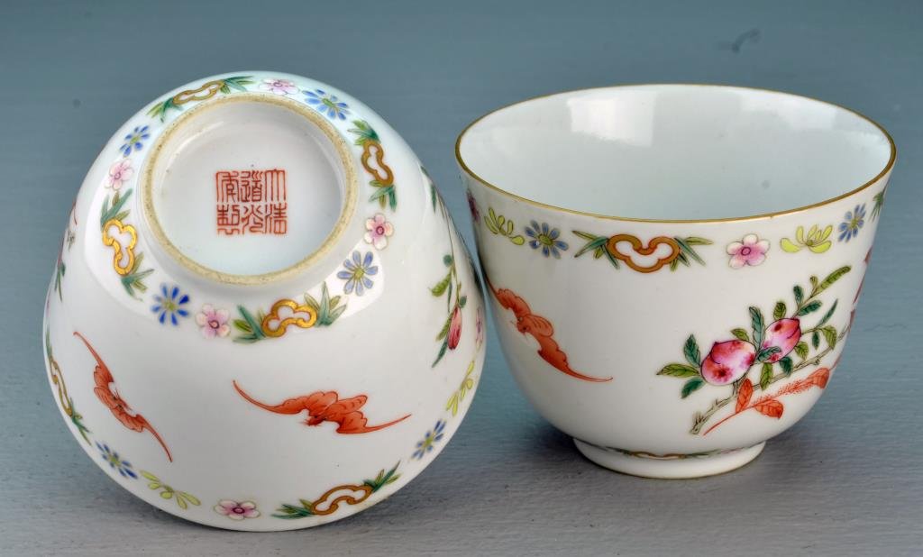 Pr. Chinese Famille Rose Porcelain Cups: Painted to depict Lotus blossoms, peaches, and iron red bats, having gilt rims, raised on short foot ring, base with iron red seal underglaze, 2.5"H X 3.5"W.