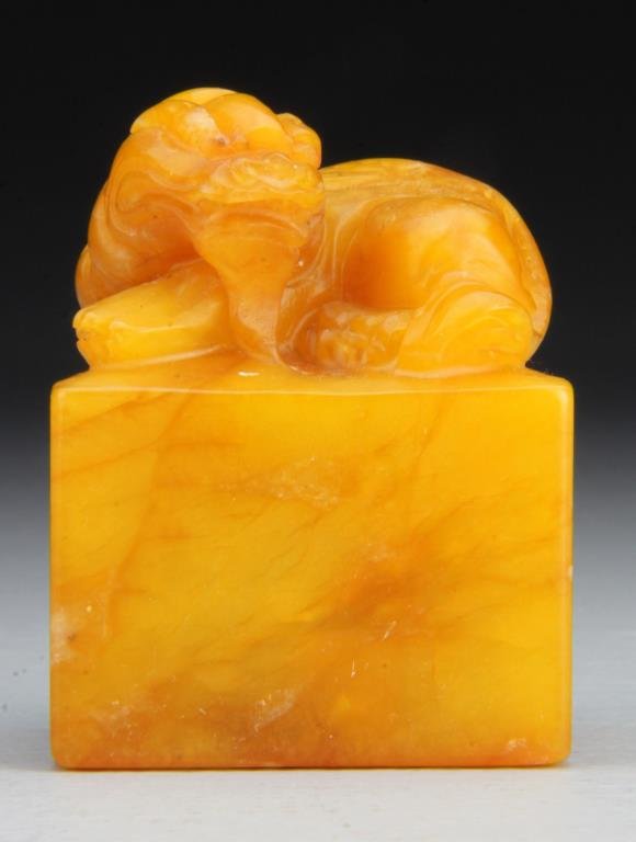 Chinese Tianhuang Stone Seal: Finely carved to depict a dragon at rest atop a square base, the stone of rich honey tone with light honey-brown vein, the seal face carved with seven characters, "chang jiang kong dai chu tian liu", 