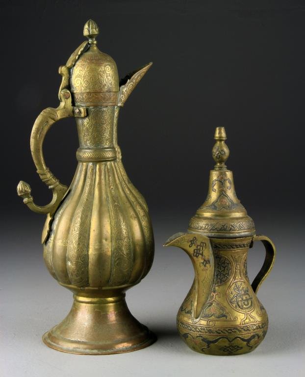 (2) Antique Islamic Ewers: One in copper and brass, having overall inlay in possibly lead, signed with two-character mark to underside and lined with tin, together with a copper example having finely chased decoration in the Is