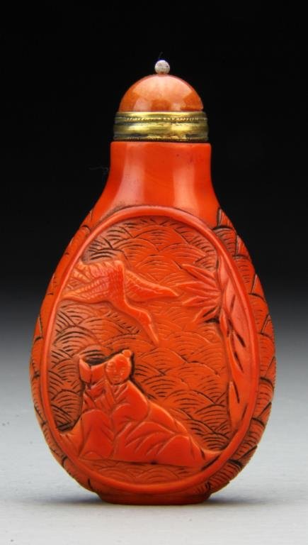 Chinese Qing Peking Glass Snuff Bottle: Carved red Peking glass snuff bottle in flattened oval shape sitting on a raised oval foot. One side depicts scholar and flying stork, other a village scene. Very well carved, topped with an orange Pe