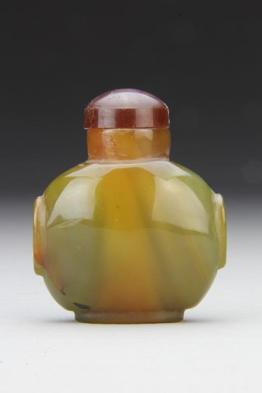Chinese Carved Agate Snuff Bottle: Finely polished and carved to show natural properties of stone, having beast head handles, complete with stopper, 2.6"H. From the collection of David Bell who worked for an Italian steel company in Ch