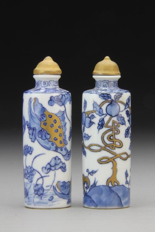 (2) Chinese Blue and White Porcelain Snuff Bottles: Two cylindrical examples finely painted to depict peaches, lotus flowers and fish with gold accents, bases having leaf in underglaze blue, tallest is 3.7"H. From the collection of David Bell who worke