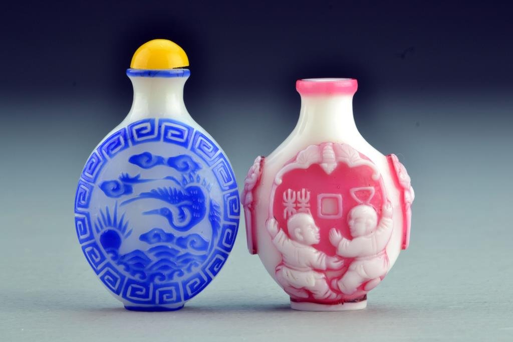 (2) Chinese Peking Glass Snuff Bottles: One with overlay depicting figures, symbols and bat, having beast head handles, second example depicting crane and ruyi clouds over water, tallest is 2.75"H. From the collection of David Bell who work