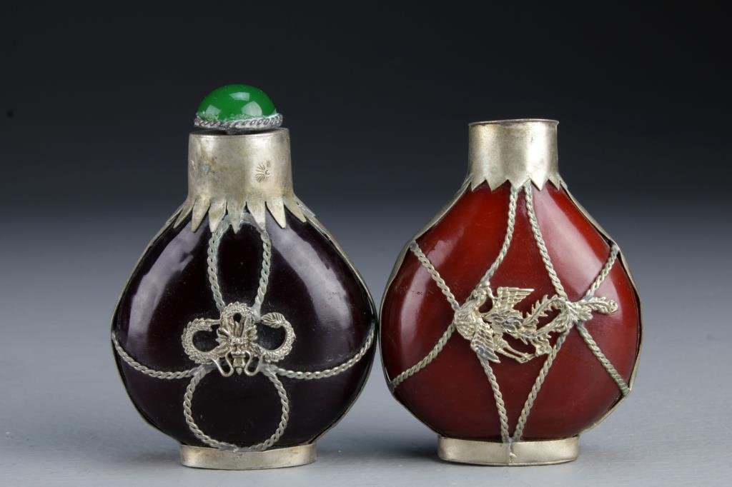 (2) Chinese Peking Glass Snuff Bottles: Having metal fixtures depicting phoenix, beast head and dragon, bases bear worn marks, one has stopper and metal spoon, tallest is 3.4"H. From the collection of David Bell who worked for an Italian st