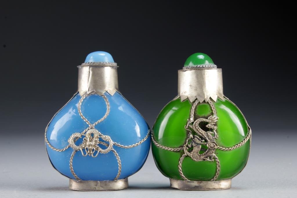(2) Chinese Peking Glass Snuff Bottles: Having metal fixtures depicting beast heads and four clawed dragons, bases with worn character marks, complete with stoppers and metal spoons, tallest is 3.2"H.