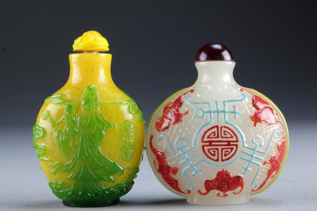 (2) Chinese Peking Glass Snuff Bottles: One finely molded and painted to depict bats and Shou symbol, the other having overlay depicting Guanyin with ruyi clouds, bird and a seal to the reverse side, tallest is 3"H.