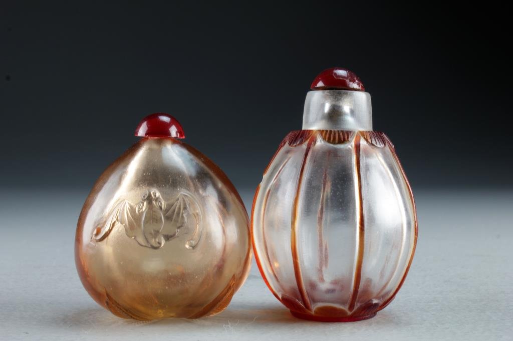 (2) Chinese Peking Glass Snuff Bottles: Two clear glass examples, one formed as upside-down peach molded with stem and leaves to base, having bats on body of bottle, the second example having overlay of lines and scalloped border at neck an