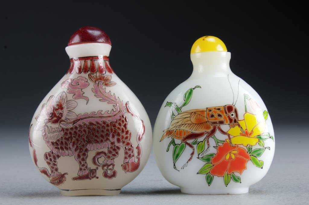 (2) Chinese Peking Glass Snuff Bottles: One finely painted to depict foo lion with ruyi cloud, the second depicting cricket with flowers and radish, bases character marked in iron red, one underglaze, tallest is 3.1"H.