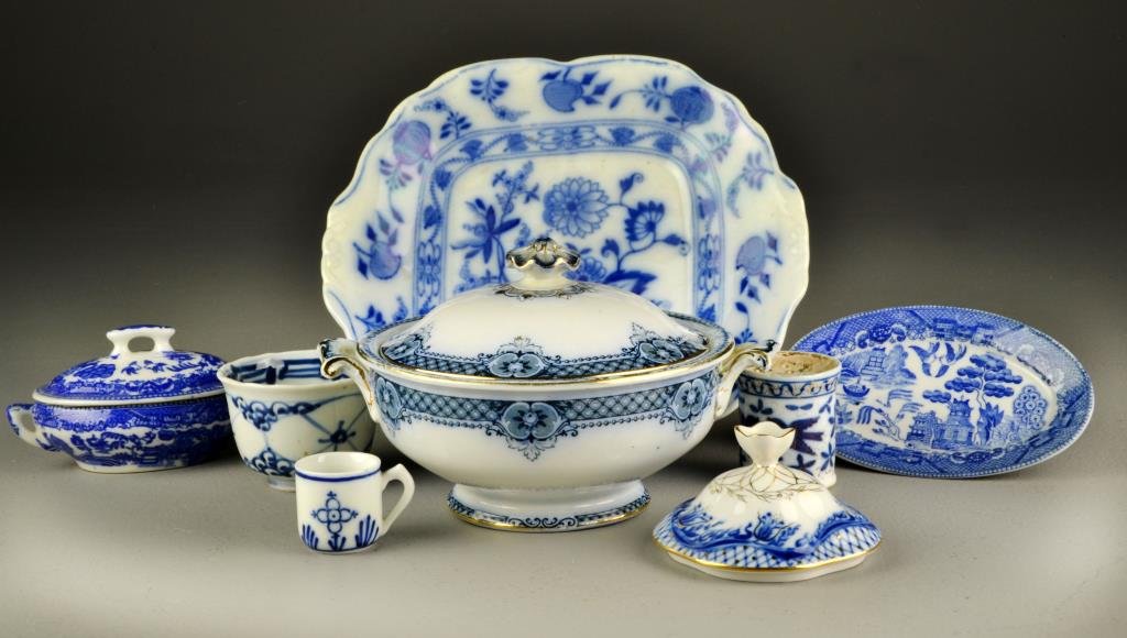 (8) Pcs. Flow Blue & Blue Willow Porcelain Table: To include a Meissen England flow blue serving plate, a flow blue and gilt covered tureen, a flow blue and gilt hat pin holder with stylized birds, a blue willow covered bowl and underplate, and vario