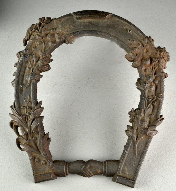 An Antique Cast Iron Horseshoe: A decorative cast iron horseshoe with floral motif and symbol of two shaking hands at base, measures 12"H, circa 20th century. Good overall condition, some areas of wear and rust.