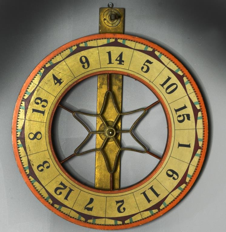 An Antique American Painted Gaming Wheel: Hand painted in ochre and red with black numerals, having cast iron insert in star form, mounted on wooden wrought iron base, wheel measures 24"D, circa late 19th-early 20th century.