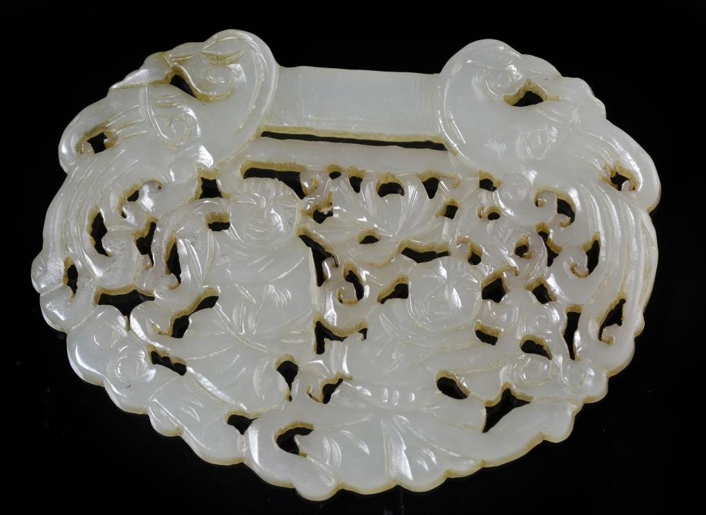 A Finely Carved Chinese Jade Plaque: A finely carved jade plaque depicting smiling figures among bats and scrolling tendrils, having a bird to each side of top bar, measures 2.6"L.