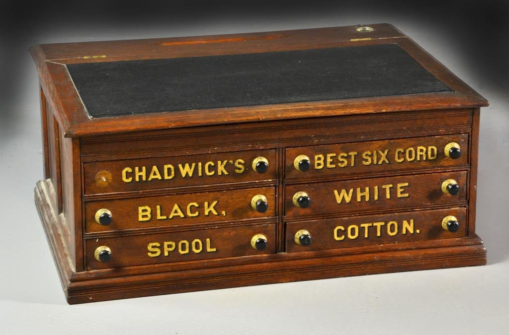 Antique Chadwick's Six-Drawer Wood Spool Cabinet: Having a slanted and hinged top with a black leather writing surface and a moulded pen tray and inkwell, opens to reveal a shallow storage space, below having six dovetailed drawers labeled for spool,