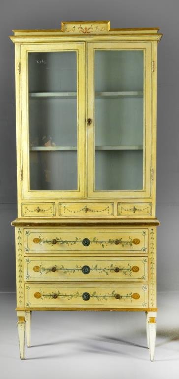 A Fine Italian Polychrome Painted Petite Cabinet: Having a carved and painted cornice above two glazed doors with two interior shelves, the base with three small drawers above three long drawers, finely painted in floral and swag motif with gilt high