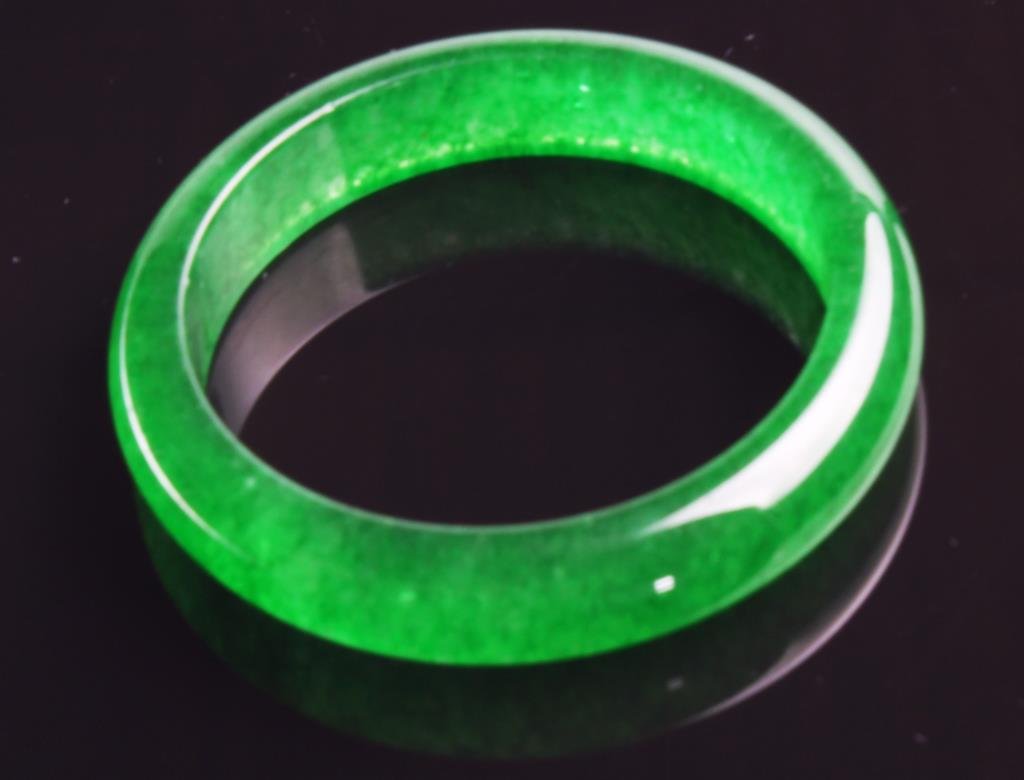 Chinese Carved Jadeite Bangle Bracelet: Finely carved and polished, the stone a dark apple green, outside diameter 3"D, inside diameter 2.5"D. Private Collection Glencoe, Illinois.