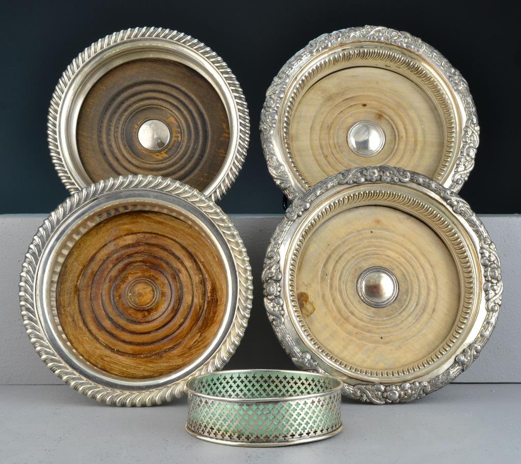 (5) Antique Sterling and Silverplate Wine Coasters: To inlcude four silver plate coasters having scalloped and floral decorated rims, all having turned wood inset, apparently unmarked, together with a sterling silver coaster having pierced cross decora