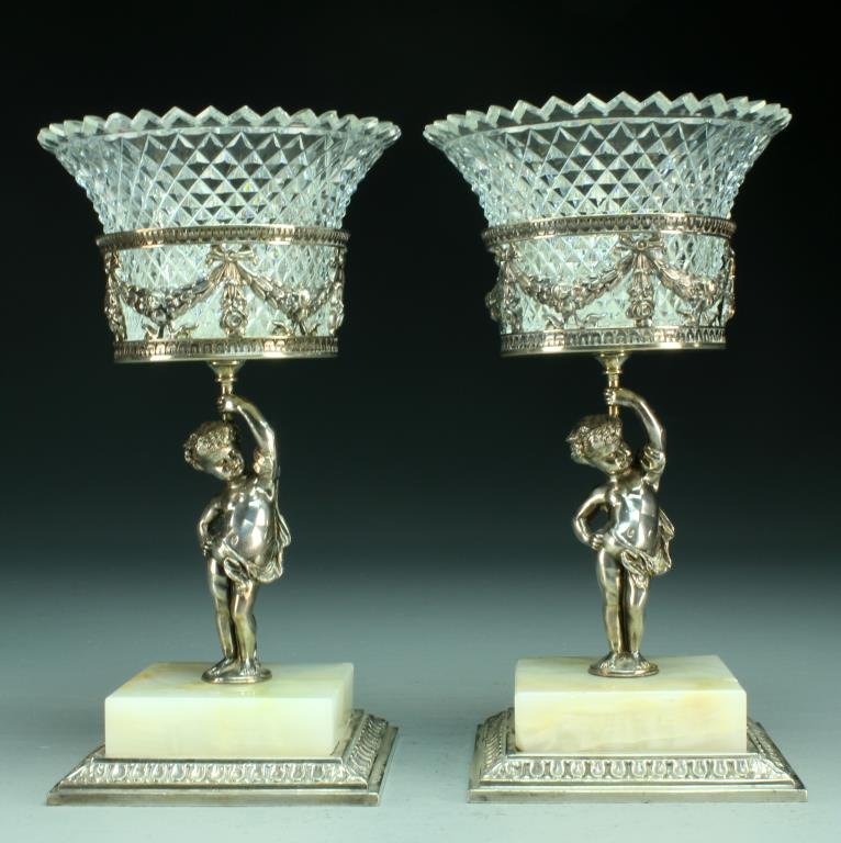 Pair Pairpoint Cut Glass and Marble Compotes: Having flared cut glass insets raised on silver plated bronze figural stands with pierced swag motif atop square marble and silver plate bases, each measures 9.5"H, circa late 19th-early 20th century.