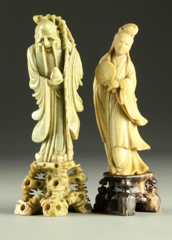 (2) Chinese Qing Carved Soapstone Figures: One depicting a beauty holding a fan, the other depicting an emancipated man holding a peach, largest measures 8.375"H, circa late 19th-early 20th century.